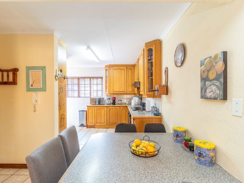 Open plan kitchen and dining area featuring traditional wooden cabinetry, laminate countertops, and tiled flooring in a functional layout.