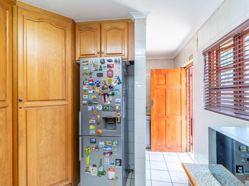 A functional kitchen area featuring traditional wooden cabinetry, tiled wall finishes, and direct access to an exterior door.