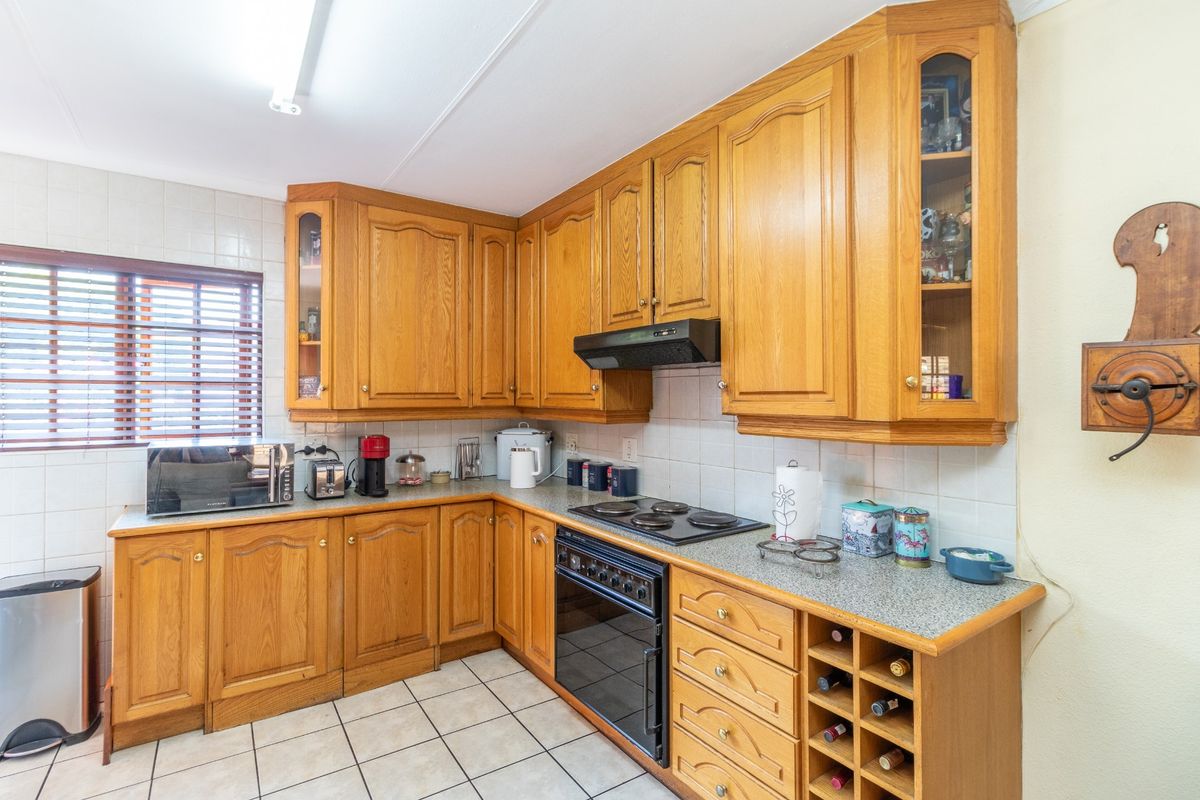 A functional kitchen featuring traditional wooden cabinetry, laminate countertops, built-in oven with hob, and tiled flooring.