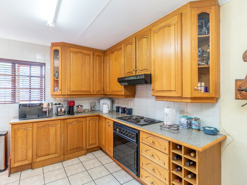 A functional kitchen featuring traditional wooden cabinetry, laminate countertops, built-in oven with hob, and tiled flooring.