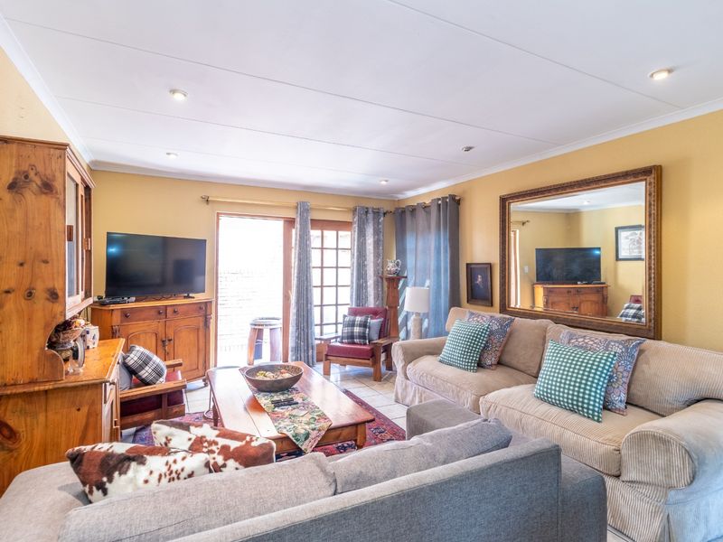 A comfortable living room featuring tiled flooring, recessed lighting, and a sliding glass door providing access to the outdoor area.