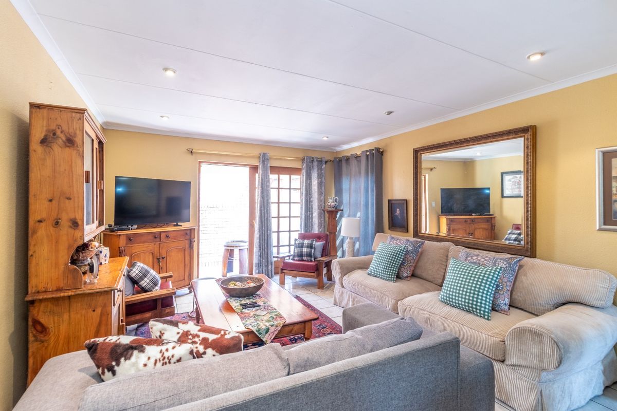 A comfortable living room featuring tiled flooring, recessed lighting, and a sliding glass door providing access to the outdoor area.