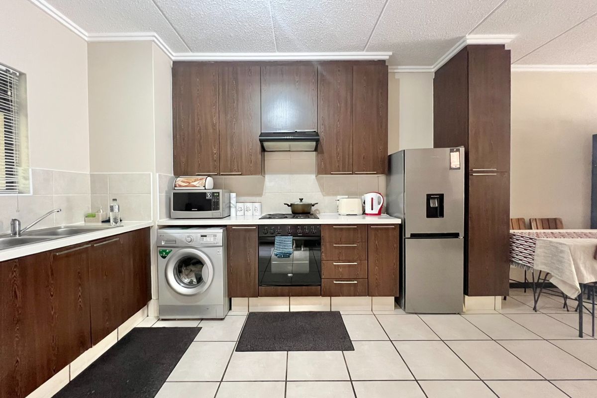 A functional kitchen featuring dark wood-look cabinetry, built-in oven with extractor fan, tiled flooring, and a double sink with tiled backsplash.