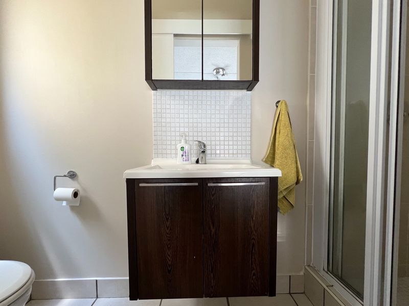 A functional bathroom featuring a dark wood vanity cabinet, mosaic tile splashback, mirrored medicine cabinet, and a separate shower enclosure.
