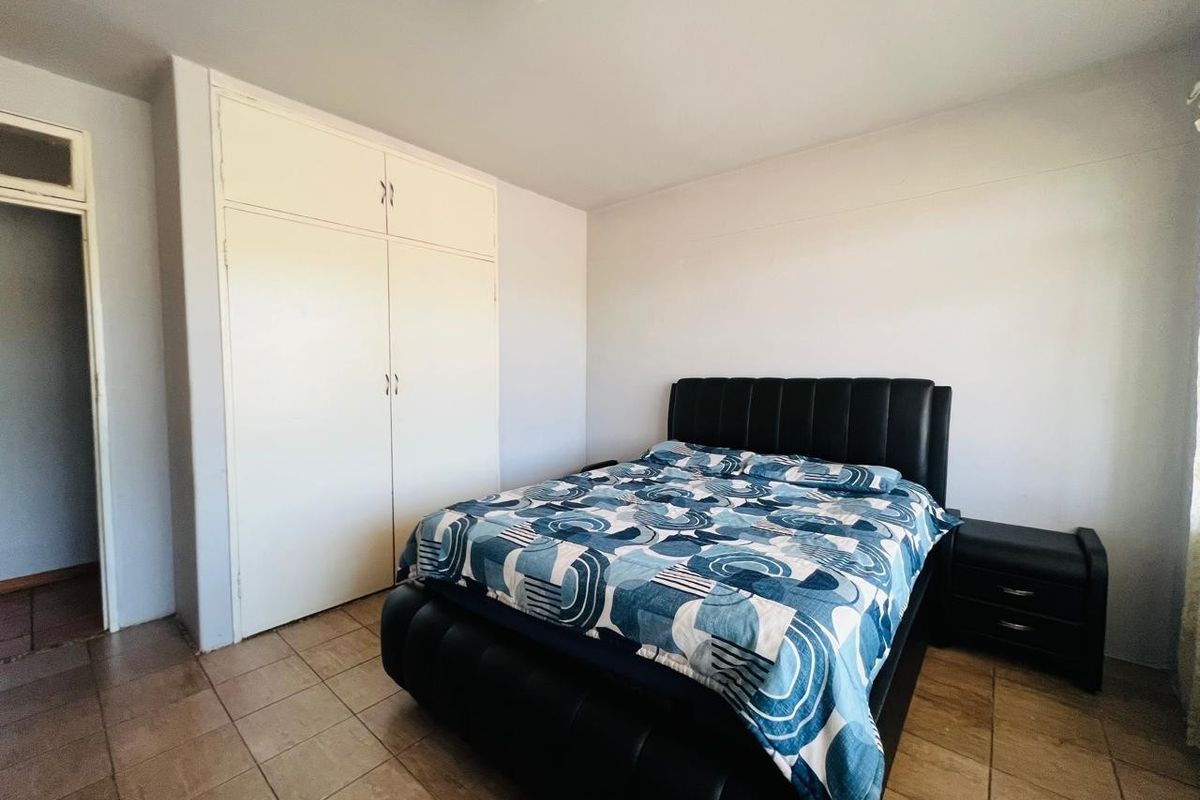A functional bedroom featuring tiled flooring and a built-in wardrobe, offering a neutral base for personalization.