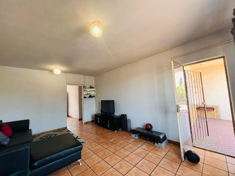 A living room featuring tiled flooring and direct access to an outdoor balcony through a security gate.