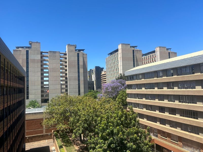 An elevated urban view overlooking surrounding apartment buildings and mature trees in a residential neighborhood.