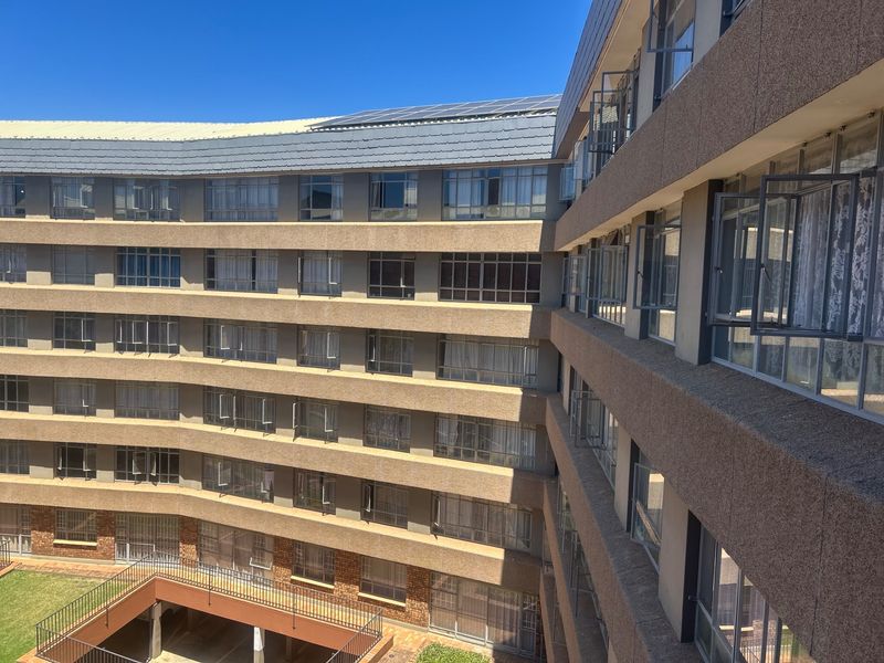 Exterior view of a multi-story apartment building featuring a curved facade, metal window frames, and rooftop solar panels.