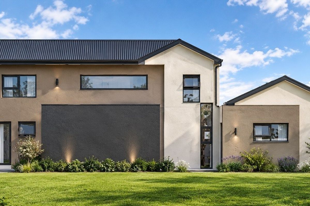 Modern two-story residential exterior featuring a combination of textured render finishes, dark metal roofing, and large aluminum-framed windows overlooking a manicured lawn.