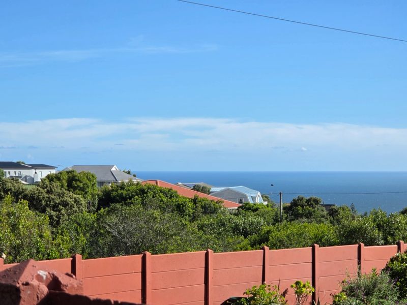 A scenic elevated view overlooking the surrounding neighbourhood with a clear horizon line of the ocean in the distance.