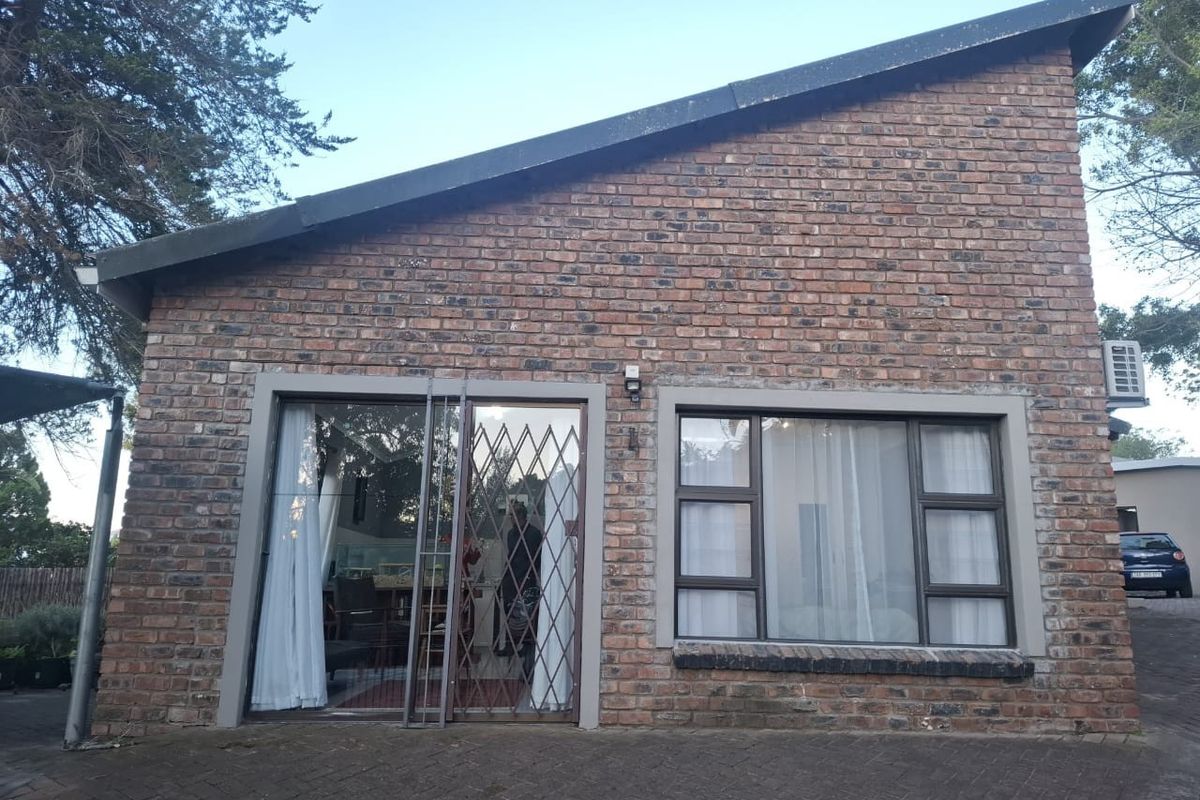 Exterior view of a face brick apartment facade featuring a sliding glass door with security gate and aluminium framed windows.
