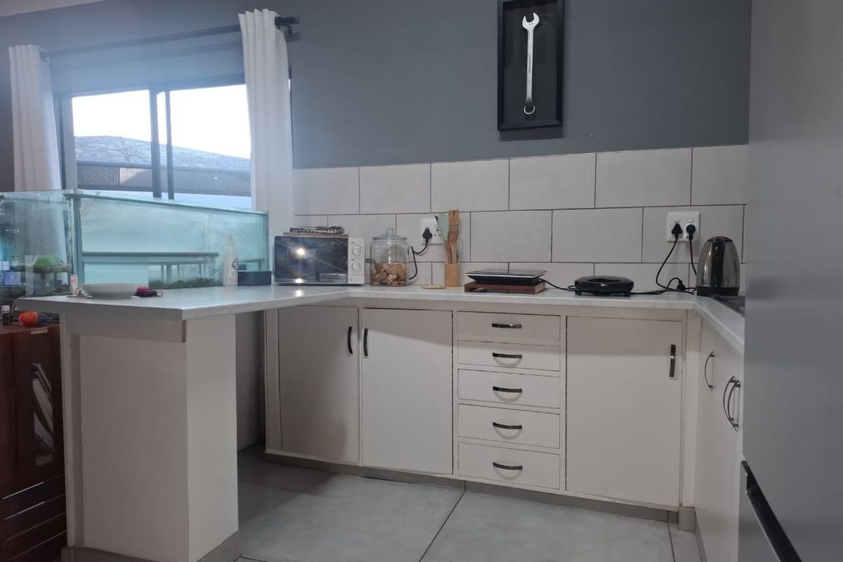 A functional kitchen featuring white cabinetry, a subway tile backsplash, and a breakfast bar extension, providing a practical workspace for daily meal preparation.