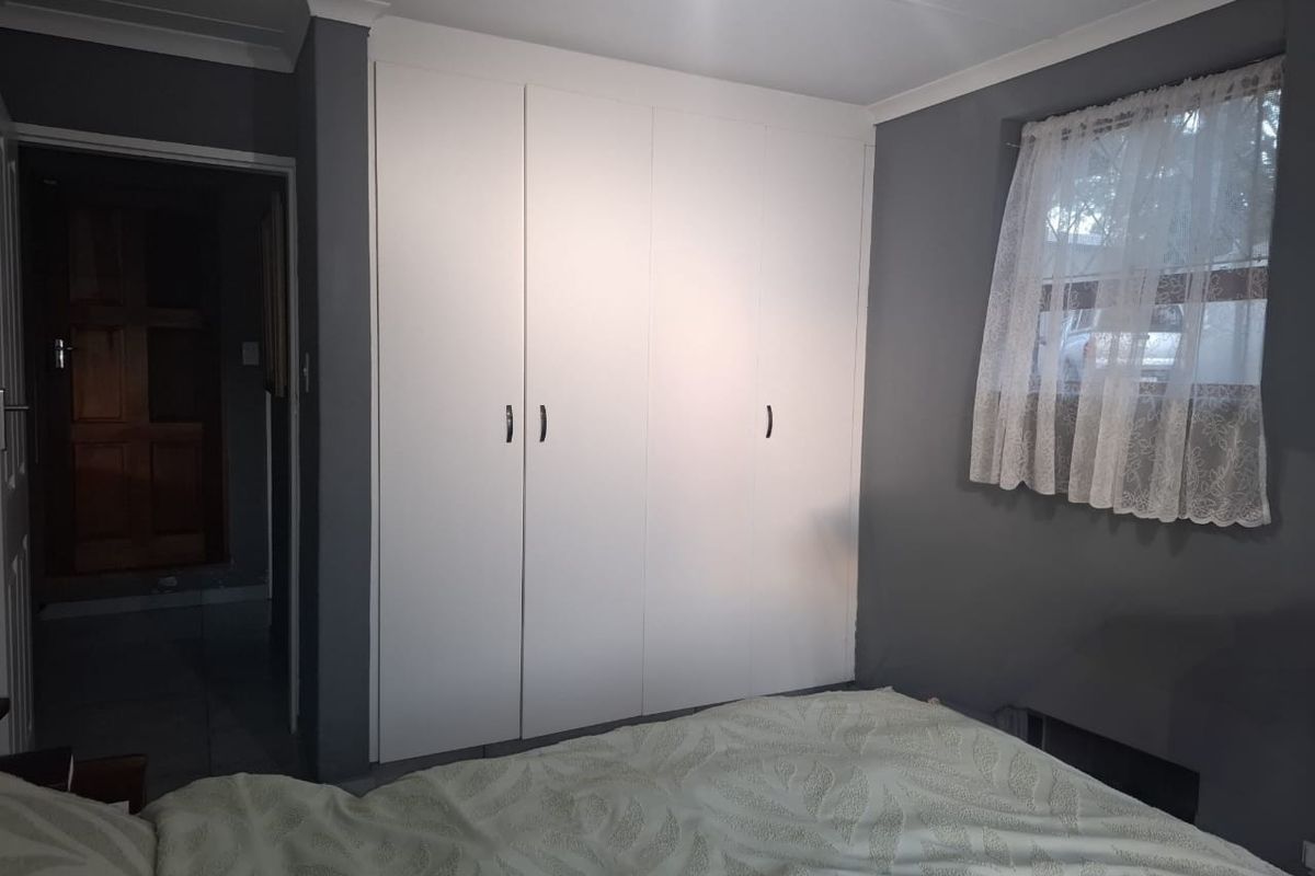 A bedroom featuring built-in white cupboards and grey painted walls, providing a neutral foundation for interior design.