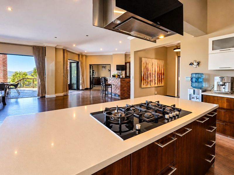 Spacious open-plan kitchen and living area featuring a central island with gas cooktop, modern cabinetry, and seamless flow to an outdoor patio.
