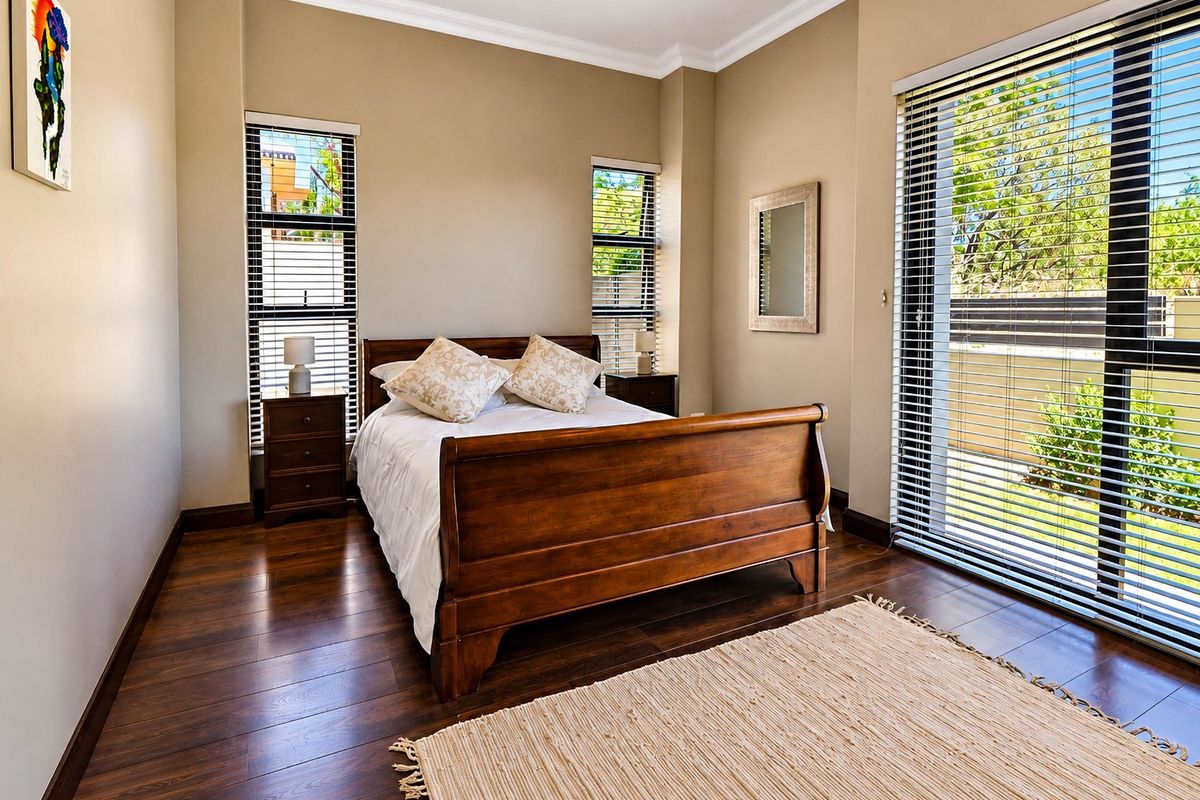 A well-maintained bedroom featuring rich hardwood flooring, crown molding, and large sliding glass doors that provide ample natural light and garden access.