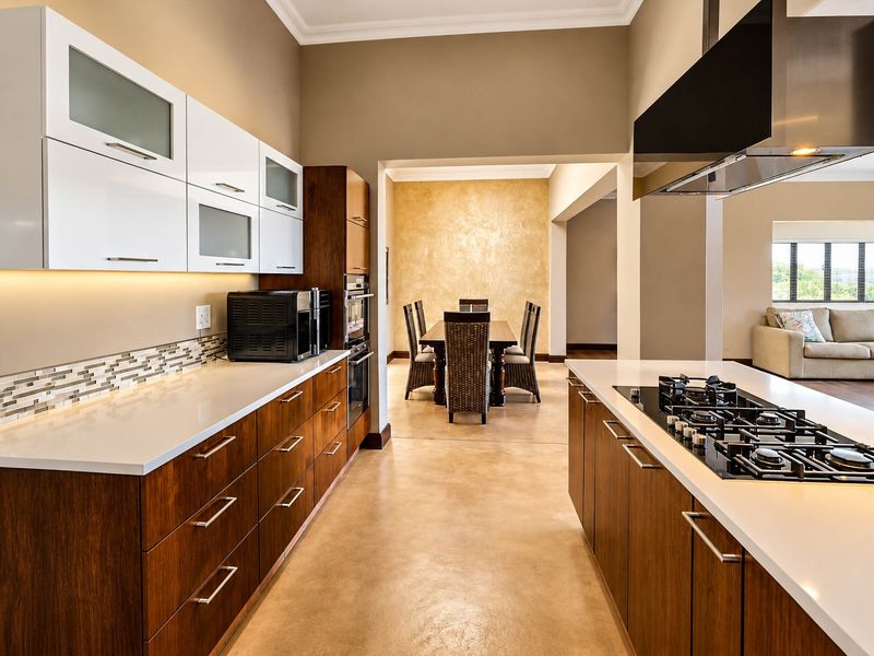 Modern open-plan kitchen featuring high-end cabinetry, stone countertops, integrated gas cooktop, and polished concrete floors, flowing seamlessly into the dining and living areas.