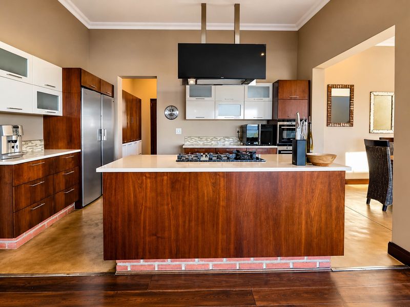 Modern kitchen featuring a central island with gas cooktop, sleek wood-finish cabinetry, stone countertops, and integrated appliances, offering a functional and stylish cooking space.