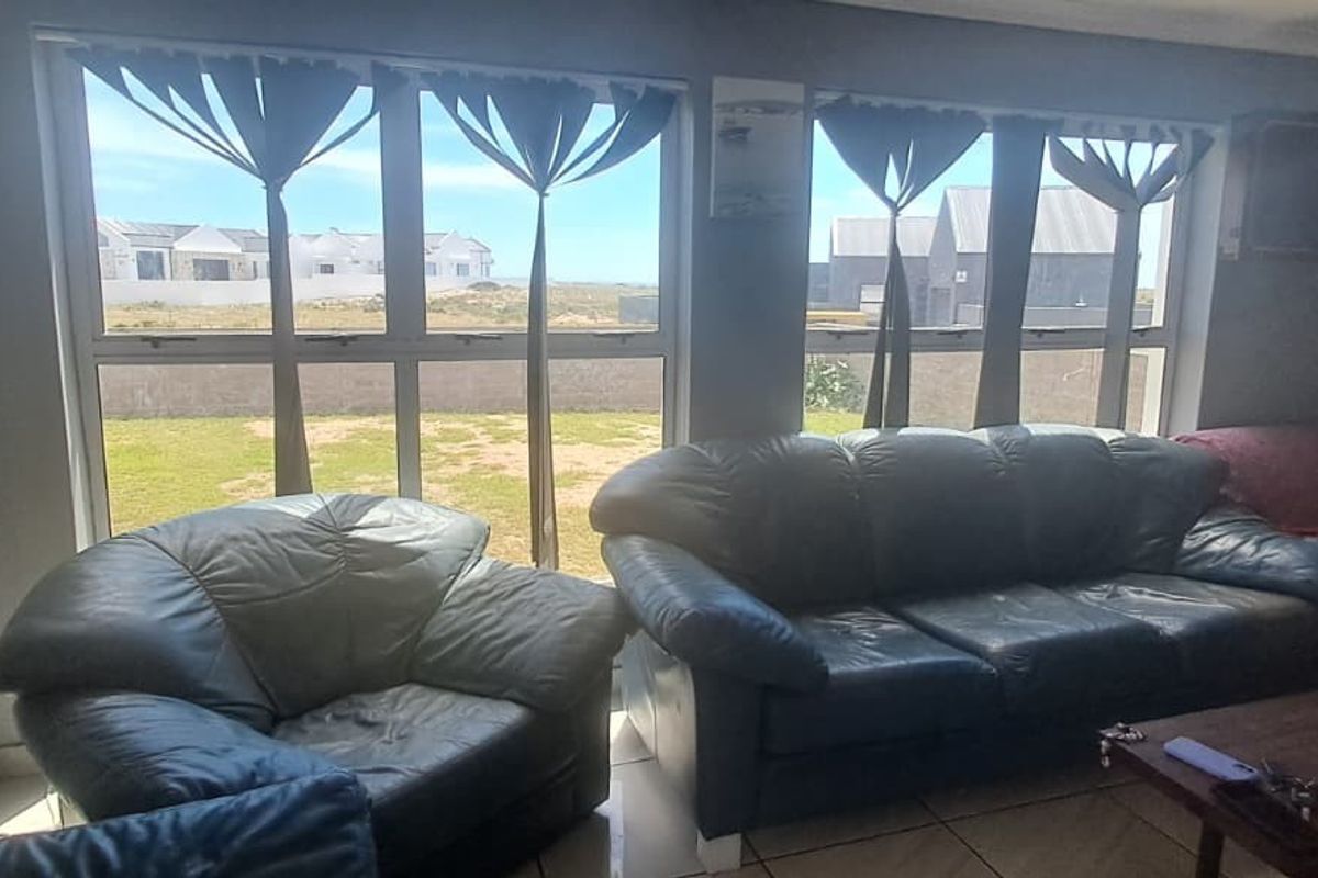 A living room featuring large windows that provide natural light and views of the garden and surrounding neighborhood.