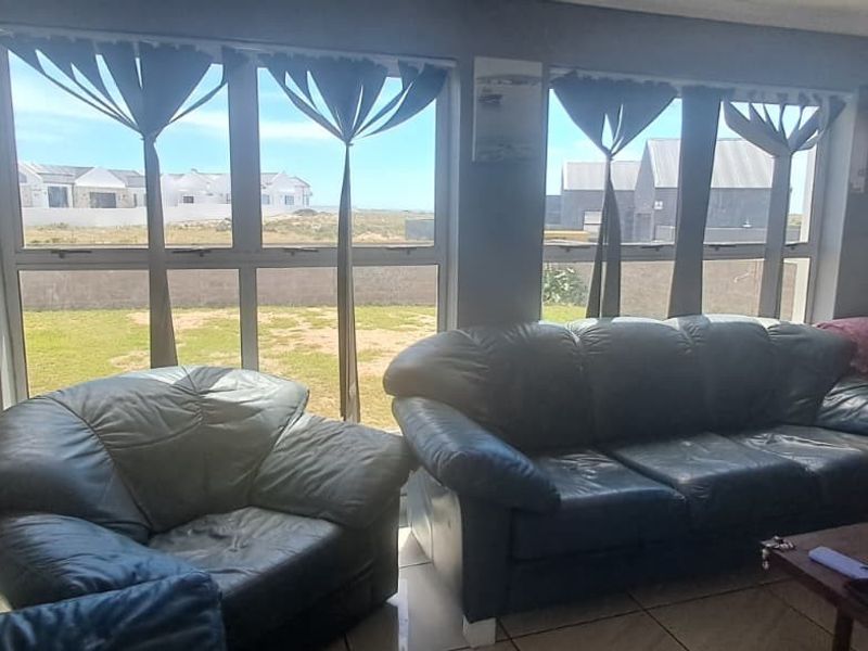 A living room featuring large windows that provide natural light and views of the garden and surrounding neighborhood.
