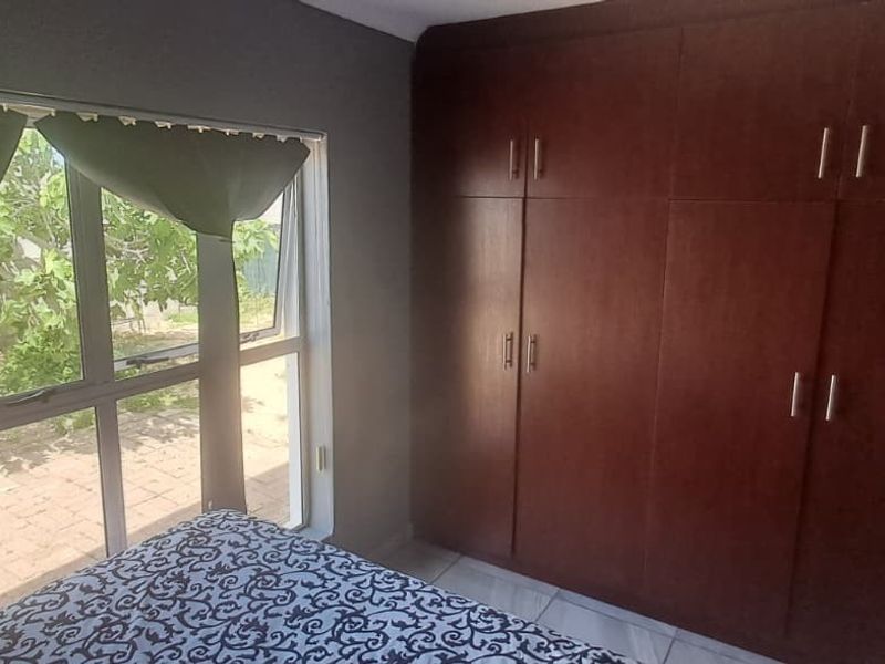 A bedroom featuring large windows providing natural light and extensive built-in wooden cupboards for storage.