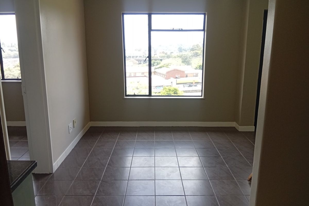 An empty living area featuring dark tiled flooring and a large window providing natural light and an urban view.