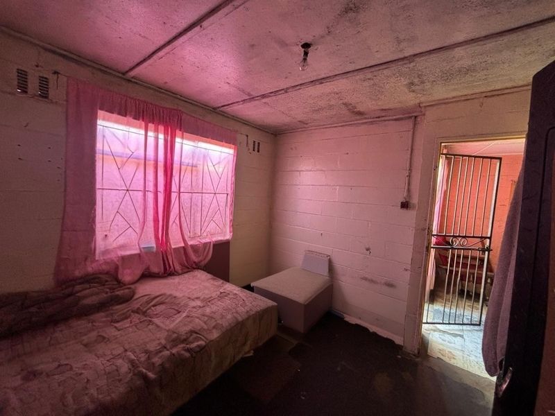 A bedroom featuring exposed brick walls and ceiling panels, requiring significant renovation and cosmetic updates to improve the overall condition and appeal.