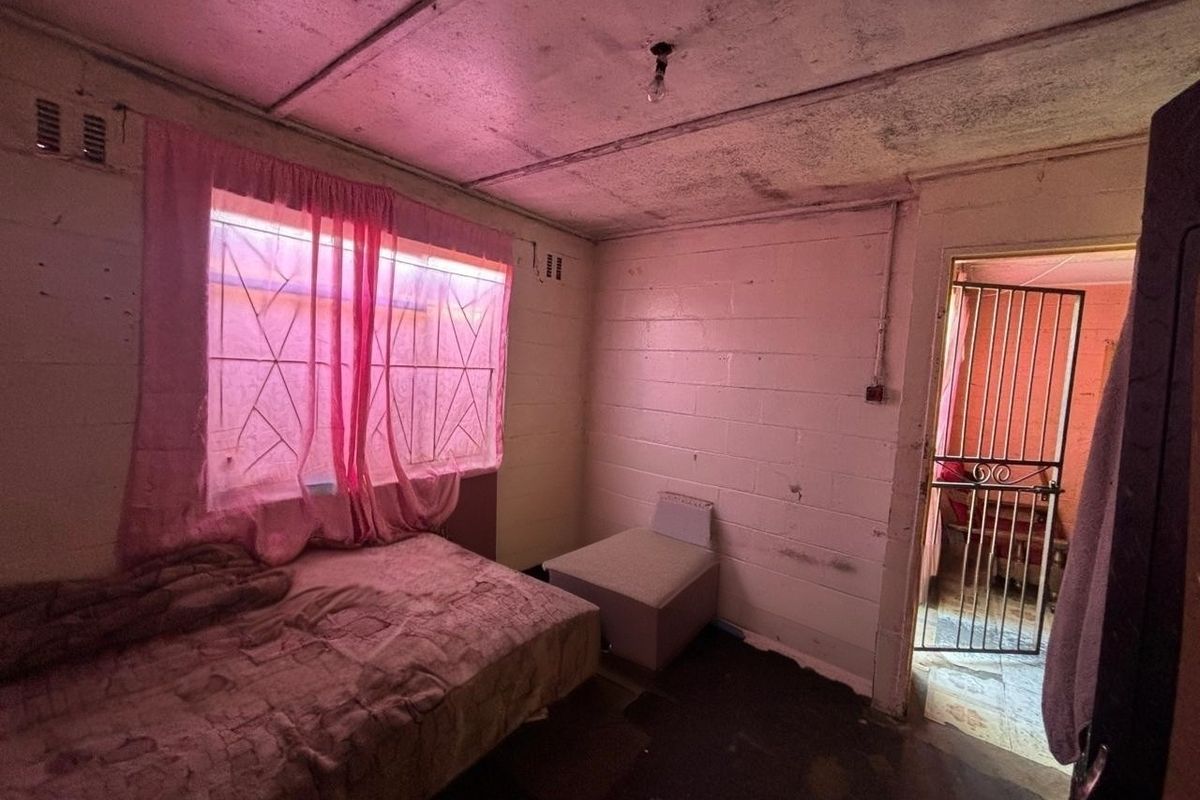A bedroom featuring exposed brick walls and ceiling panels, requiring significant renovation and cosmetic updates to improve the overall condition and appeal.