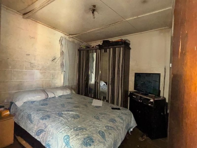 A bedroom space requiring significant renovation, featuring worn wall and ceiling finishes and dated flooring, offering potential for a complete modern update.