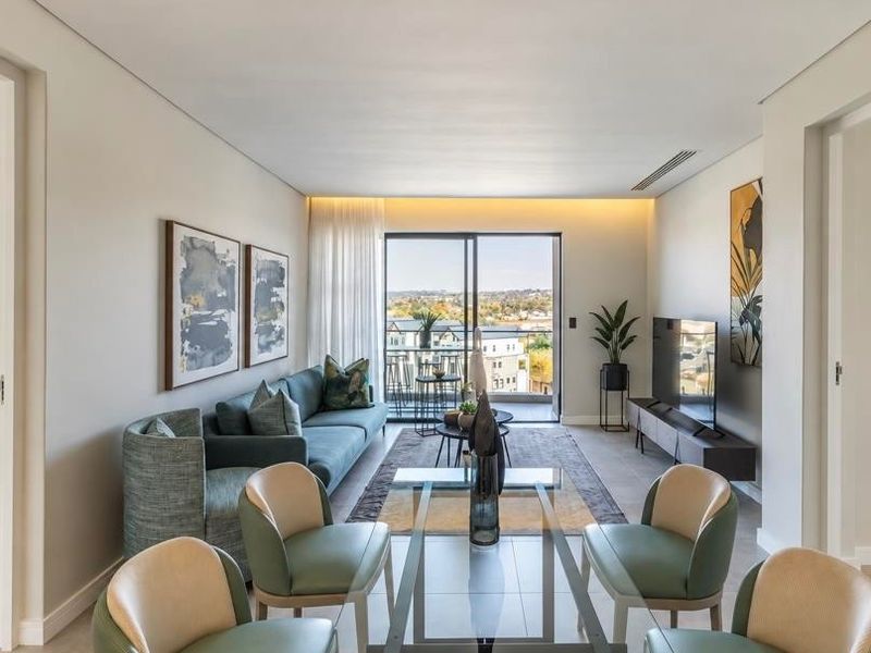 Modern open-plan living and dining area featuring sleek tiled floors, recessed lighting, and large sliding glass doors leading to a private balcony.