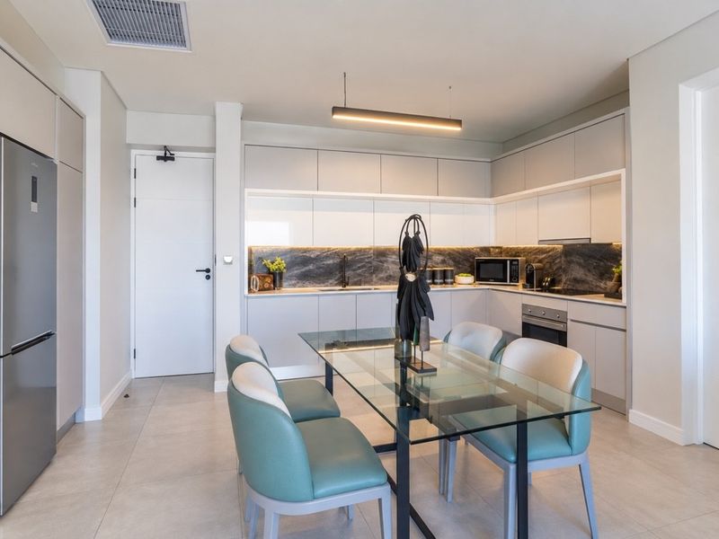 Modern open-plan kitchen featuring sleek cabinetry, stone backsplash, integrated appliances, and recessed lighting, seamlessly flowing into the dining area.