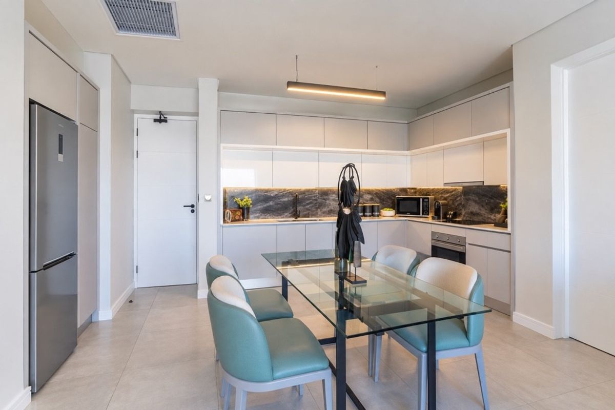 Modern open-plan kitchen featuring sleek cabinetry, stone backsplash, integrated appliances, and recessed lighting, seamlessly flowing into the dining area.