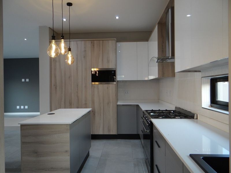 Modern kitchen featuring sleek two-tone cabinetry, stone countertops, a central island, and integrated appliances including a gas hob and built-in oven.