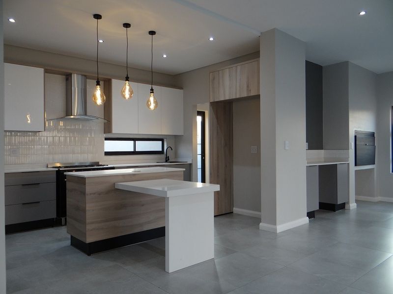 Modern, high-end kitchen featuring sleek cabinetry, a central island with breakfast bar, stone countertops, and integrated lighting in a contemporary open-plan layout.
