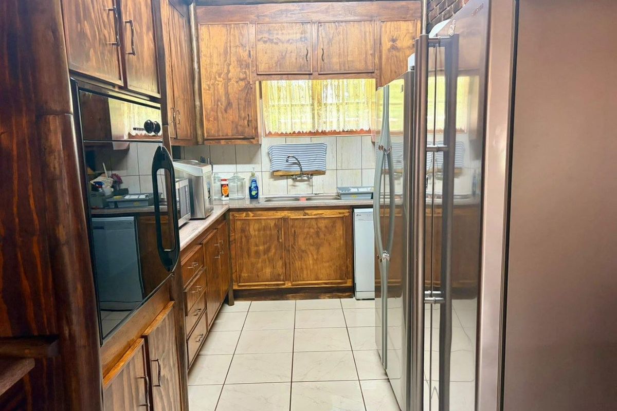 A functional kitchen featuring traditional wooden cabinetry, tiled flooring, a double basin sink, and a built-in oven, offering a classic farm-style aesthetic.