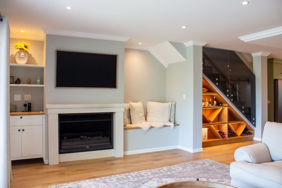 A well-appointed living room featuring a built-in fireplace, custom cabinetry, and elegant under-stair storage with integrated lighting and a modern glass balustrade.