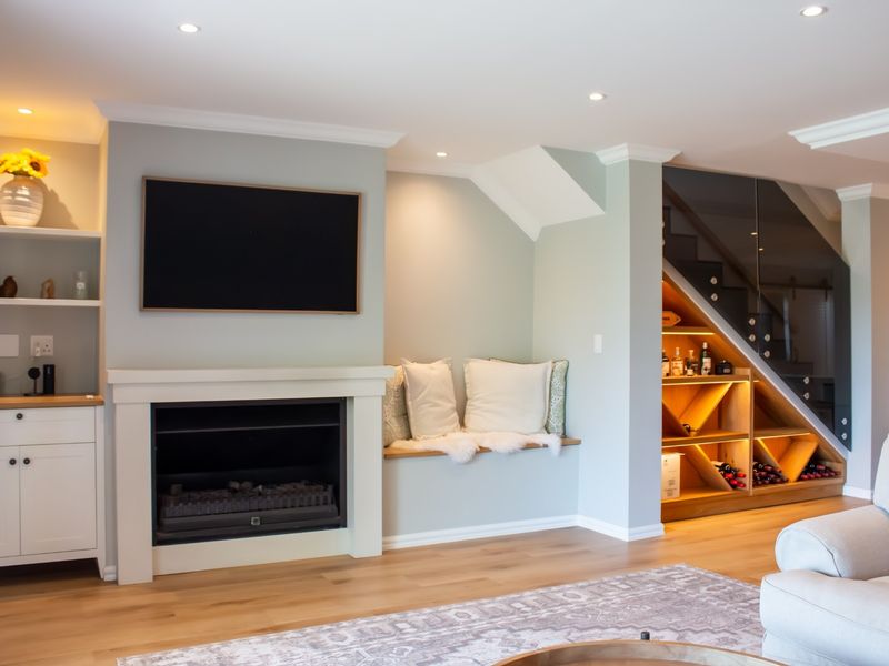 A well-appointed living room featuring a built-in fireplace, custom cabinetry, and elegant under-stair storage with integrated lighting and a modern glass balustrade.