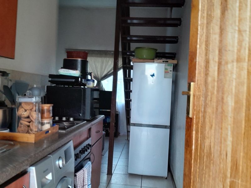A compact kitchen area featuring built-in cabinetry, a hob, and an oven, with an adjacent staircase leading to another level.