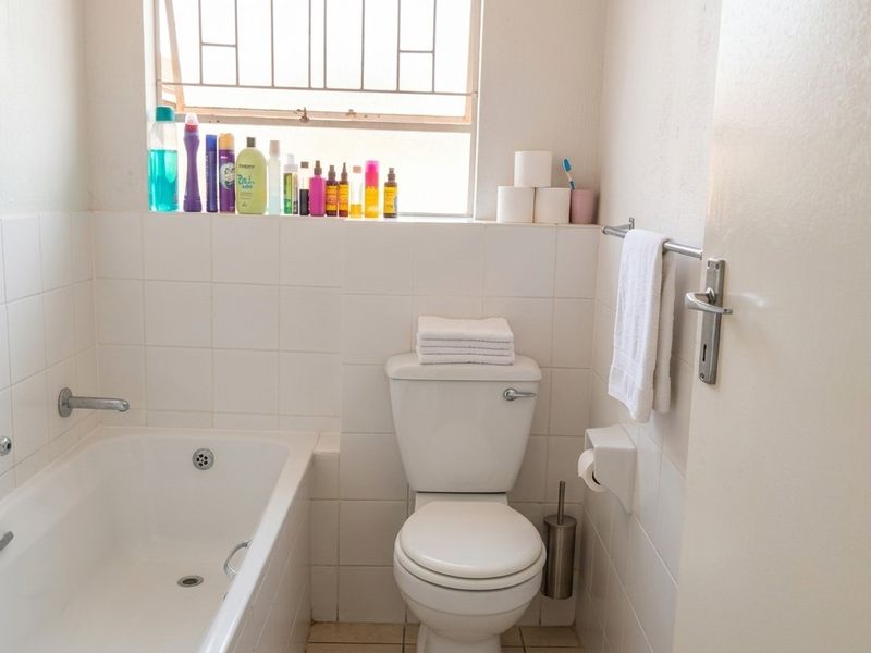 A functional bathroom featuring a standard bathtub, toilet, and tiled wall finishes with a window providing natural light.