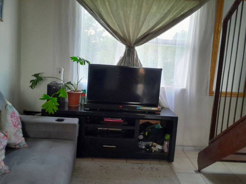 A living room area featuring tiled flooring and an internal staircase, providing a functional space for relaxation.