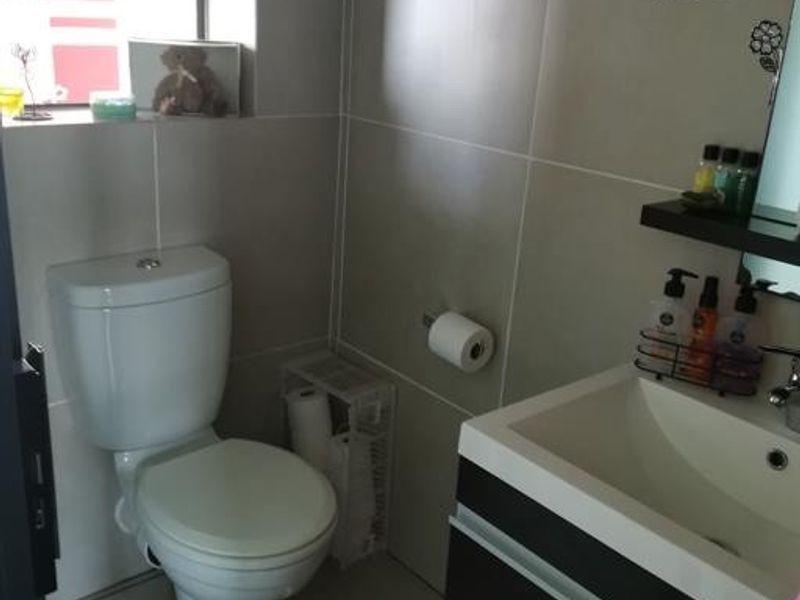A compact, modern bathroom featuring tiled walls, a contemporary vanity with basin, and a white toilet.