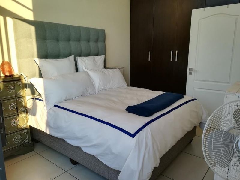 A well-lit bedroom featuring neutral tiled flooring and dark wood built-in cupboards, providing ample storage space.