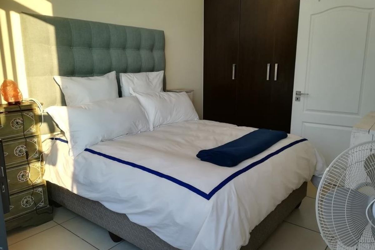 A well-lit bedroom featuring neutral tiled flooring and dark wood built-in cupboards, providing ample storage space.