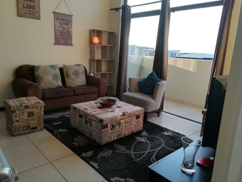 A bright living room featuring large sliding glass doors that provide access to an outdoor balcony and allow for ample natural light.