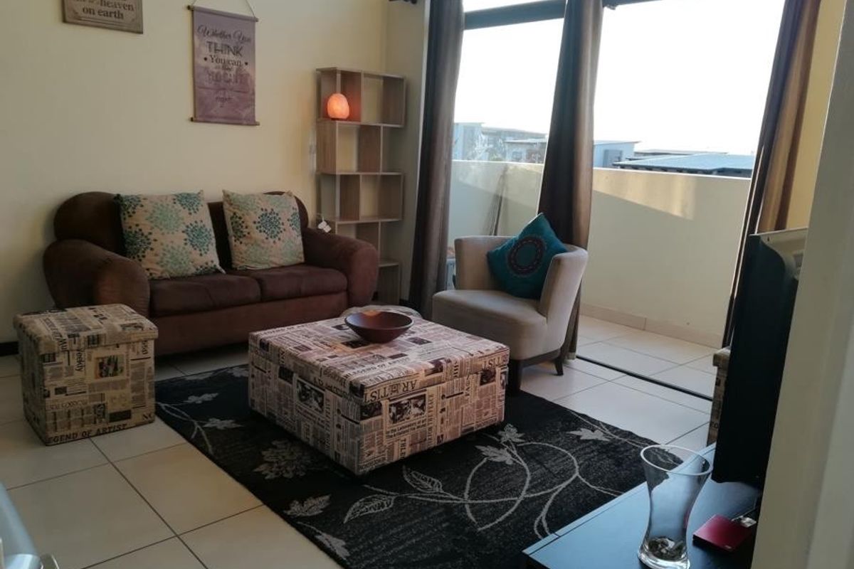 A bright living room featuring large sliding glass doors that provide access to an outdoor balcony and allow for ample natural light.