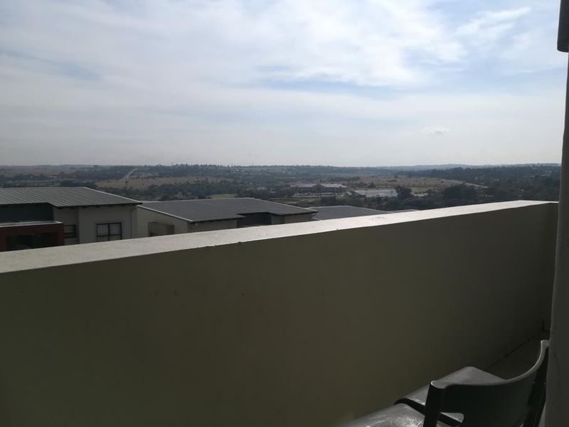 A balcony featuring a solid balustrade and tiled flooring, offering an expansive elevated view of the surrounding landscape.