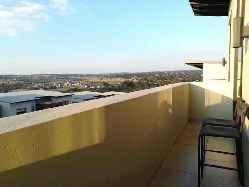 A spacious balcony featuring tiled flooring and a parapet wall, offering expansive elevated views of the surrounding landscape.