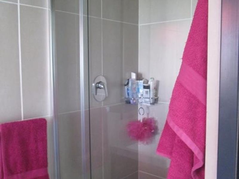 A clean bathroom featuring a glass-enclosed shower with modern chrome fixtures and neutral wall tiling.