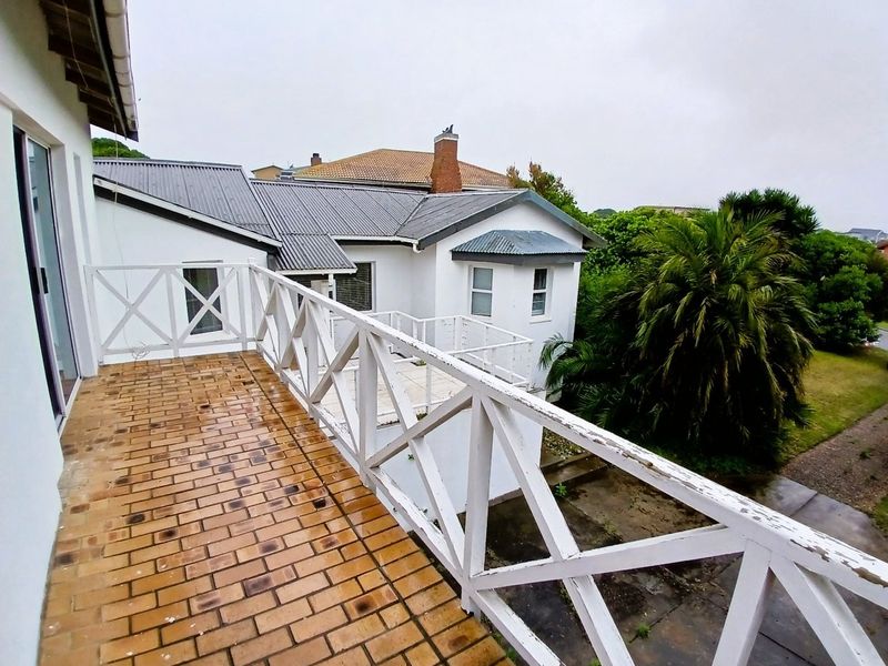 An elevated balcony featuring brick paving and a white timber balustrade, overlooking the rear garden area.