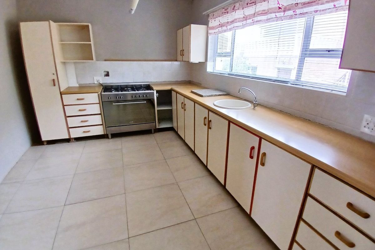 A functional kitchen featuring built-in cabinetry, laminate countertops, a gas stove, and tiled flooring, offering a clean space ready for modernization.