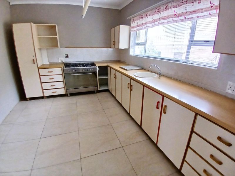 A functional kitchen featuring built-in cabinetry, laminate countertops, a gas stove, and tiled flooring, offering a clean space ready for modernization.